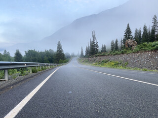 Road in the mountains in changeable weather on a foggy morning.