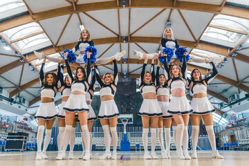 Cheerleaders doing a split while other girls holding them up in the air on the basketball court....
