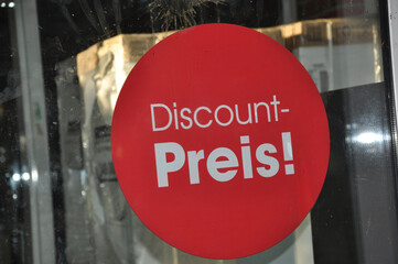 Discount Preis! Rundes  Klebeschild auf der Glastür vom Supermarkt in rot und mit weißer Schrift.