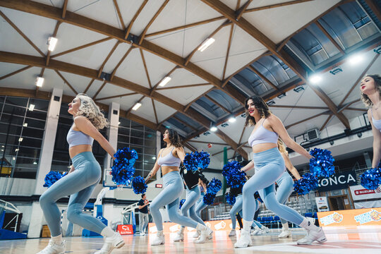 Shot taken during cheerleaders dance with pom poms on a basketball court. High quality photo