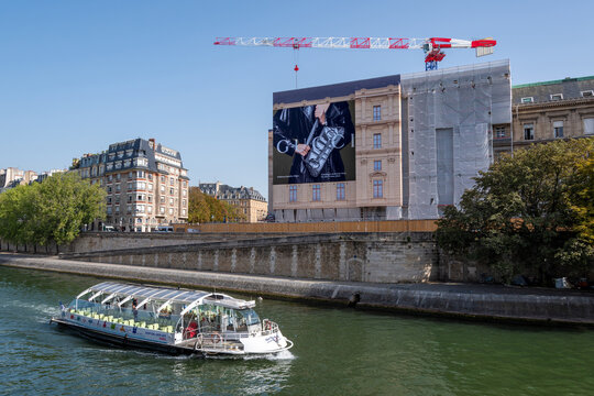 Paris, France - 6 septembre 2023: Grande affiche publicitaire de Gucci recouvrant les &eacute;chafaudages des travaux de r&eacute;novation d'un immeuble parisien. Un bateau navigue sur la Seine &agrave; l'avant plan	