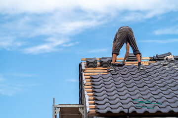 craftsman on the roof of a family house, building a roof covering from ceramic tiles, copy space
