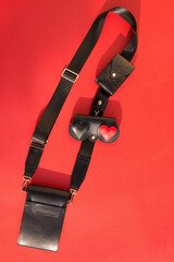 A smartphone bag made of black leather with red inserts on the strap