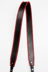 Black leather bag strap with red decoration, close-up on white background