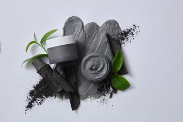 Against the gray background, bamboo charcoal and tea leaves decorated on gray background. Mockup jar for advertising and design label. Concept for cosmetic of natural ingredients.