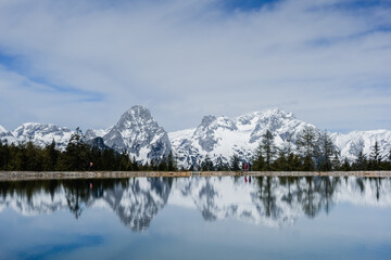 reflections in a mountain lake from a snowy mountain range in austria