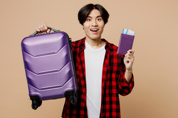 Traveler man wear red casual clothes hold bag passport boarding ticket isolated on plain pastel...