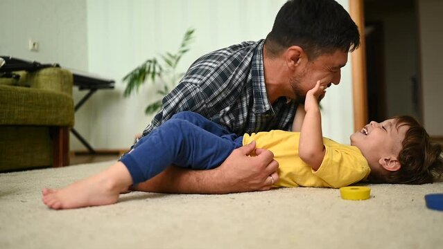 Father and son bond over playtime, sharing laughter and joy on the comfortable living room floor