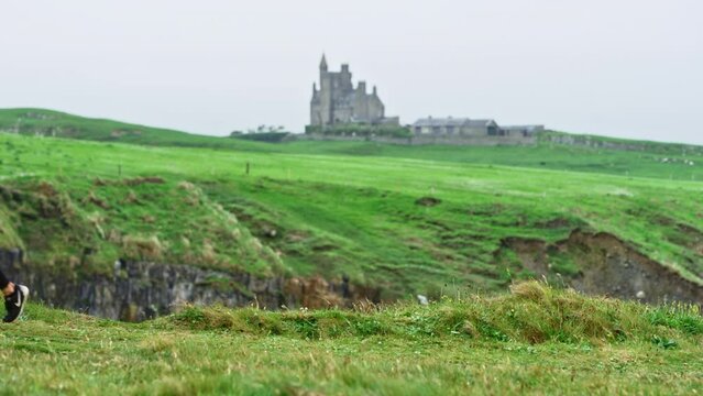 Classiebawn Castle In Distance, Woman Walks By Cliffside