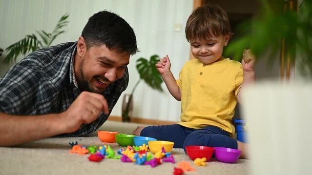 Father and son sorting toys by color into matching bowls for a fun and educational activity