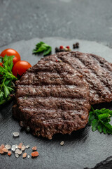 Grilled beefsteaks cutlets patties on a dark background, vertical image. top view. place for text