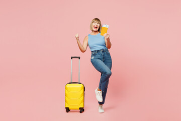 Traveler fun elderly woman wear blue casual clothes hold bag passport ticket isolated on plain pink...