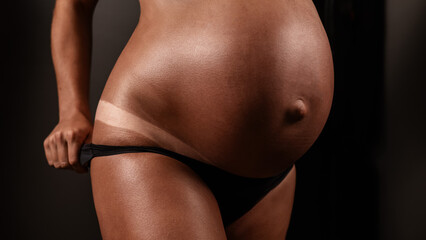 Naklejka premium Pregnant woman pulls back her panties showing instant tan. 