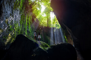 Fototapeta premium Young couple tourism with rays of light enjoying Tukad Cepung Waterfall at Bali, Indonesia