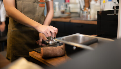 Cropped image of female barista using coffee machine in coffee shop