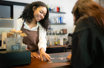 Customers select coffee items. with a young woman barista working at the coffee shop counter