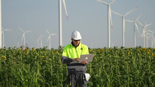Engineer in uniform with laptop on a background of wind park