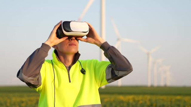 Engineer wearing virtual reality glasses in the field of wind turbines