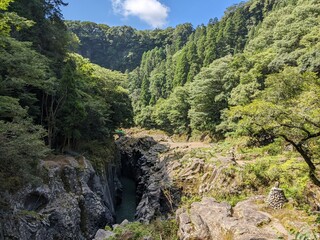 Fototapeta na wymiar Takachiho Gorge, a narrow chasm cut through the rock by the Gokase River and partway along the gorge is the 17 meter high Manainotaki waterfall cascading down to the river below