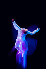 Freedom of movements. Young man in stylish clothes in motion against black studio background in neon with mixed lights effect. Concept of movements, art, dance and sport, fashion, youth, ad