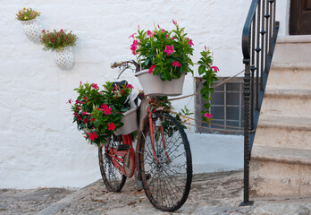 Fototapeta na wymiar old bicycle is decorated with fresh flowers on the street near the house