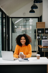 Young attractive Asian woman smiling thinking planning writing in notebook, tablet and laptop working from home, looking at camera at office .