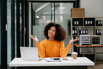 Young attractive Asian woman smiling thinking planning writing in notebook, tablet and laptop working from home, looking at camera at office .