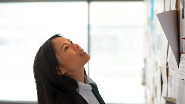 Businesswoman checking bulletin board in modern building
