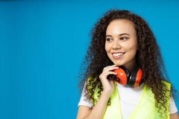 Attractive, young girl in noise-reducing headphones against a blue background