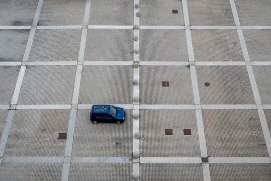 Parcheggio deserto Una sola automobile parcheggiata, isolata. Ripresa dall'alto fra le linee geometriche del pavimento.