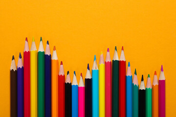 Colored wooden pencils on a yellow background.