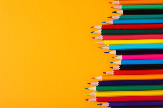Colored wooden pencils on a yellow background.