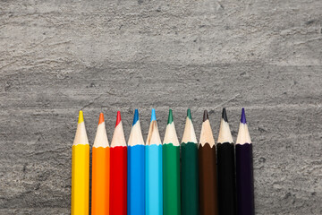 Colored wooden pencils on a gray background.