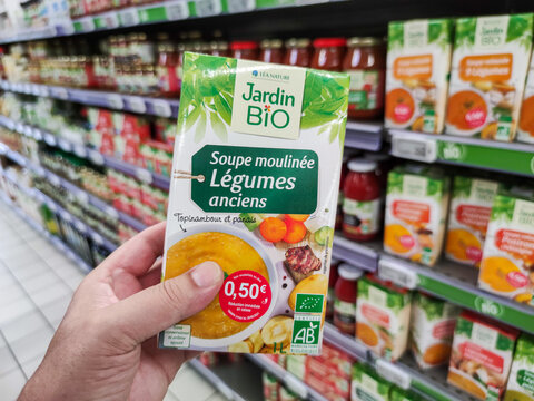 Closeup of customer hand holding an Organic Vegetable Soup with heirloom vegetables by"Jardin bio" French brand
