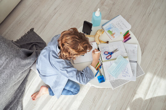 Unrecognizable boy writing in notepad during quarantine