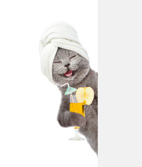 Happy cat with towel on it head holds tropic  cocktail and looks from behind empty white banner. isolated on white background
