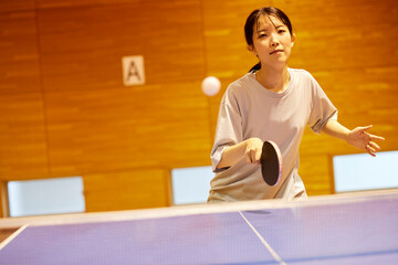 体育館にて卓球の練習をするスポーツウェアを着た日本人女性