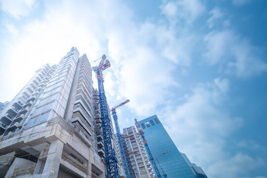 High rise building under construction. The site with cranes against blue sky.