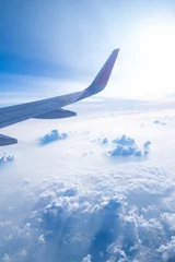Fotobehang Clear blue sky with fluffy ornamental cumulus clouds, panoramic view from an airplane, wing close-up. Dreamlike cloudscape. Travel, tourism, vacations, weekend, freedom, peace, hope, heaven concepts © Jarspics