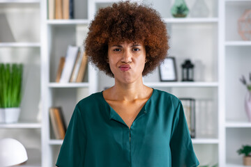 Young offended ethnic African American woman pouting looking at camera after bullying or insult or intolerance stands in office