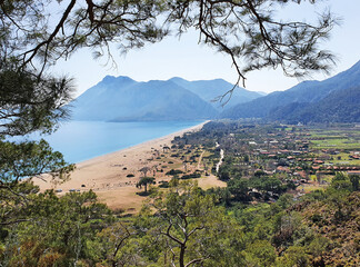 Thу stunning picture shows the breathtaking view of a valley with bright sea and  lush green mountains.