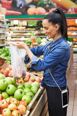 Delightful Hispanic woman buying apples in grocery store