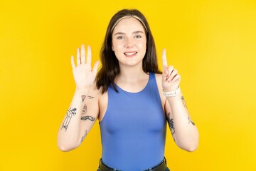 Beautiful woman wearing blue tank top showing and pointing up with fingers number six while smiling...