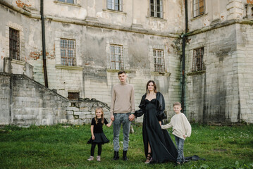 Fototapeta na wymiar Mother, father, daughter, son stands near ancient palace. Mom, dad hugging happy kid in nature autumn day. Childs embrace parents near old Pidhirtsi Castle, Lviv Ukraine. Family spending time together