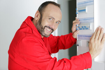 happy young male electrician working on fusebox