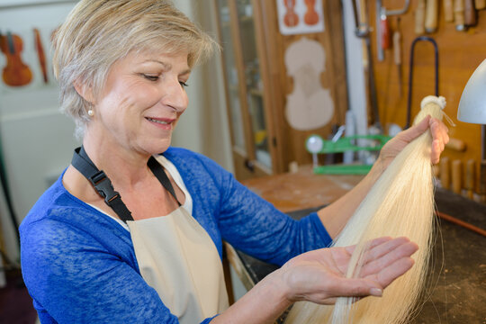 Woman examining fibres in instrument workshop - Powered by Adobe