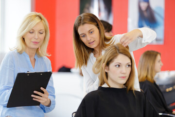 supervisor observing young lady training to become a hairdresser