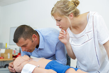 cpr practice of woman and man on cpr baby dummy