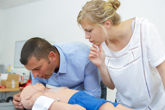 cpr practice of woman and man on cpr baby dummy