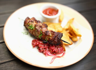 On plate there is kebab potato salad and there is ketchup next to it. Lunch menu concept